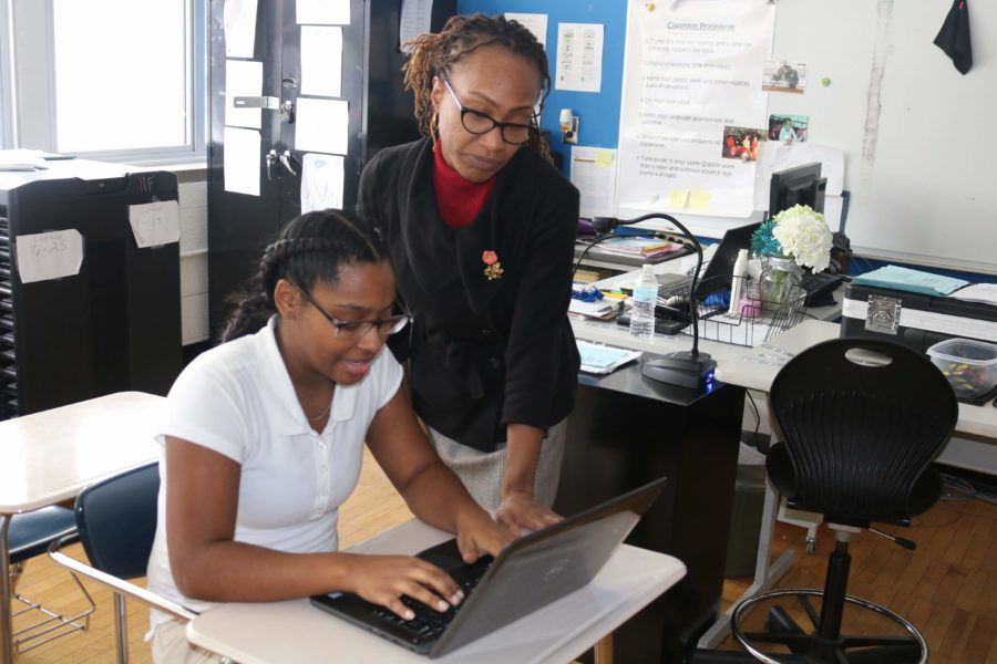 teacher working with student on a laptop